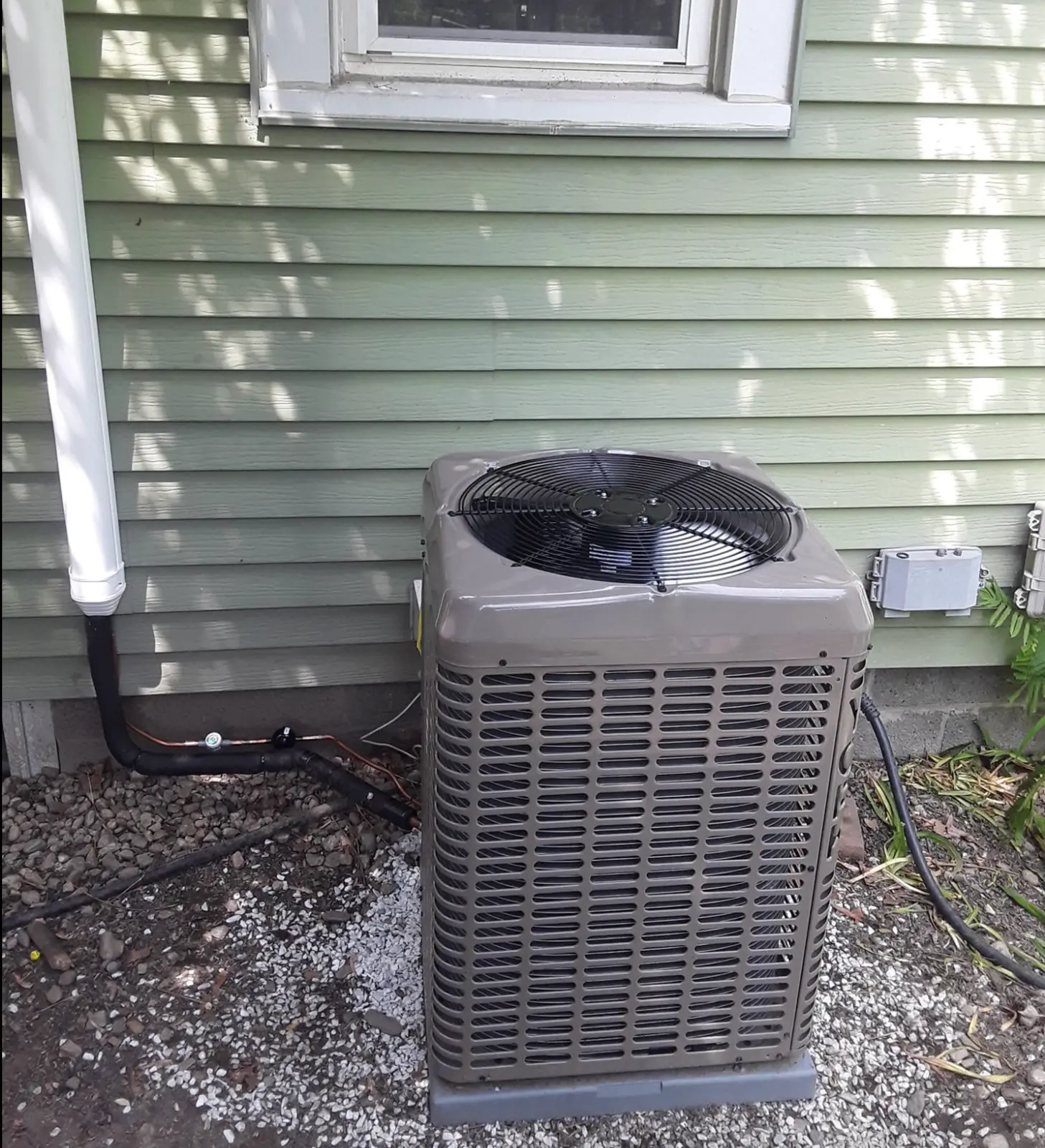 Residential outdoor air conditioning condenser beside a home